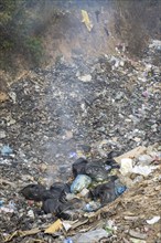 Coking rubbish dump, rubbish pit with waste and plastic rubbish, karst landscape near Vang Vieng,