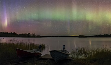 Aurora Borealis, northern lights or aurora borealis, lake with boats on the shore, Finland, Europe