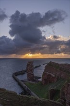 Red sandstone cliff with Lange Anna on the offshore island of Heligoland, mole as protection