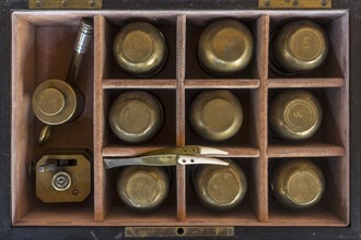 19th century cupping therapy set showing nine brass cups in antique wooden case