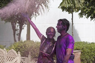 Young couple covered in colourful dye celebrating the Holi festival, Festival of Colours in