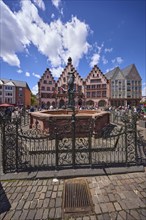 Fountain of Justice and Römer Town Hall on the Römerberg under a blue sky with cumulus clouds in