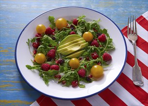 Avocado and berries salad with arugula and yellow cherry tomatoes