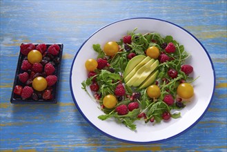 Avocado and berries salad with arugula and yellow cherry tomatoes