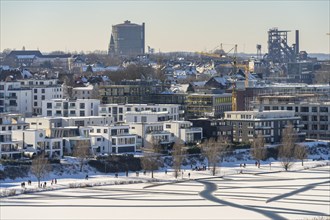 Residential buildings and pedestrians at the snow-covered and frozen Phoenix Lake in Dortmund,