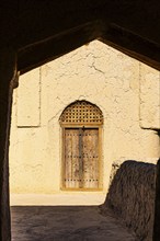 Decorated round arch entrance door in the largest preserved mud town in Oman, Al Bilaad, Al Bilaad