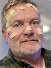 Man with many small wound patches on his face, after a laser treatment at the dermatologist, for