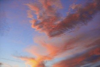 Sunset sky with orange clouds over blue background