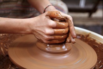 Clay potter hands closeup working on wheel handcrafts pottery work