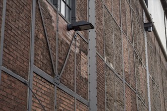 Weathered brick wall with metal supports and lamps, highlighting the industrial history of a