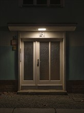 Nightly illuminated front door of a typical post-war building from the fifties in Berlin Kreuzberg