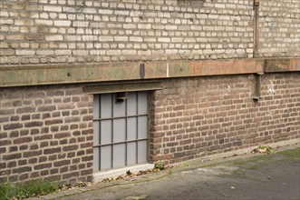 Frosted glass basement window illuminating a weathered industrial brick wall building, showcasing