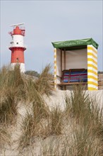 Lighthouse and beach chair on sandy dunes with grassy surroundings, Borkum, l North Sea, GERMANY