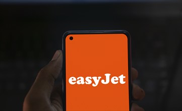 EasyJet logo is displayed on smartphone. EasyJet plc is a British multinational low cost airline