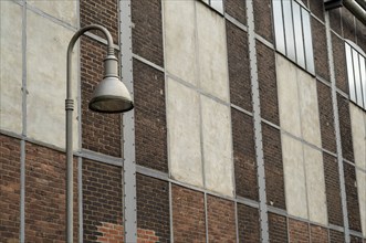 Metal street lamp illuminating an old industrial building facade with brick and concrete walls