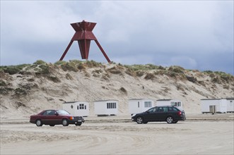 Car traffic on the beach in front of beach huts and sea mark on an early spring day in Blokhus,