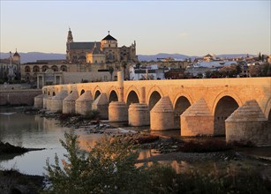 Roman bridge spanning river Rio Guadalquivir with Mezquita cathedral buildings, Cordoba, Spain,