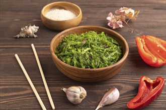 Chuka seaweed salad in wooden bowl on brown wooden background. Side view, close up