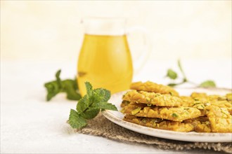 Traditional iranian dessert sohan with glass of green tea on a gray concrete background and linen