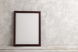 Brown wooden frame mockup on gray concrete background. Blank, vertical orientation, still life,