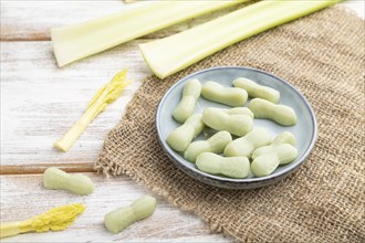 Jelly celery candies on white wooden background and linen textile. close up, side view