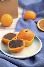 Truffle chocolate tangerine candies on a white wooden background and blue linen textile. Side view,