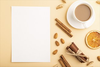 Composition with white paper sheet, almonds, cinnamon and cup of coffee. mockup on orange