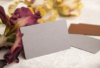 Gray business card with iris flowers on gray concrete background. side view, copy space, still life