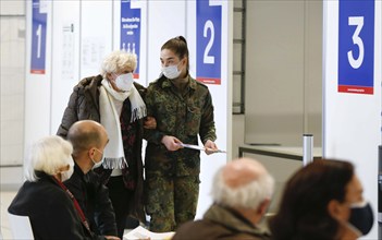 A Bundeswehr soldier brings an elderly woman to the vaccination centre in Terminal 5 of BER