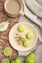 Green macarons or macaroons cakes with cup of coffee on a brown concrete background and linen