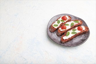 Red beet bread sandwiches with cream cheese and tomatoes on white concrete background. Side view,