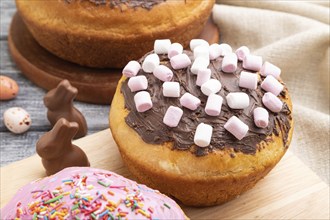 Homemade glazed and decorated easter pies with chocolate eggs and rabbits on a gray wooden