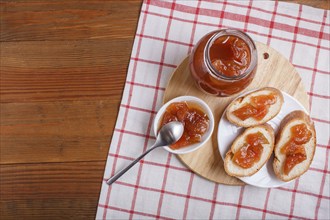 Pear jam in a glass jar on a linen tablecloth on a wooden table. Homemade, top view