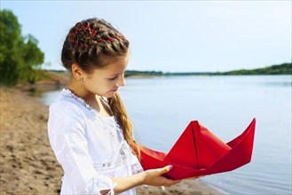 Image of lovely young girl with red paper boat