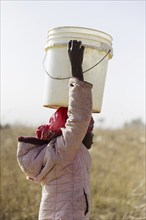 Girl carrying a heavy bucket of water on her head, Maraban Dare, 07/02/2024