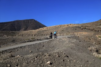 Cycling in barren landscape of Jandia peninsula Fuerteventura, Canary Islands, Spain, Europe