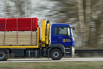 Truck, Truck MAN TGS 26.360 with building material driving fast on the motorway A92, motion blur,