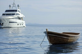 Concept for economic and social inequality showing small poor wooden fishing boat and luxury yacht