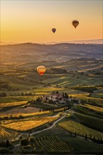 Hot air balloon drifting above undulating tuscan hills in sunsets golden light, AI generated