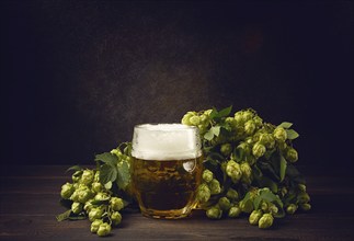 A mug of beer, on a wooden table, with a branch of fresh hops, rustic, no people