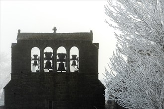 Aubrac plateau. Typical bell tower of Prinsuejols in winter. Lozere department. Occitanie. France