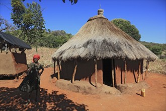 South Ethiopia, Benna people, house, hut, woman in front of her round hut in a Benna village,