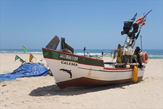 Traditional fishing boat with colourful flags on the beach, looking into the distant blue coloured