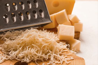 Grated cheese, Maasdam, on a cutting board, grater and cheese knife, close-up, no people