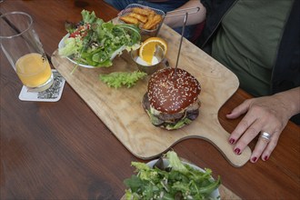 Veggie burger with fries and salad served on a wooden board, Bavaria, Germany, Europe