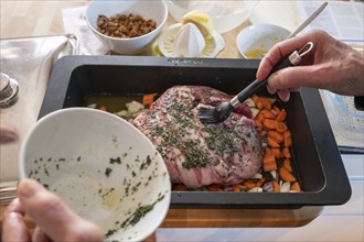 Roast lamb with herbs and vegetables in a casserole in front of roasting, Bavaria, Germany, Europe