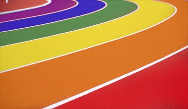 Symbolic image of queer in sport: Running track of an athletics facility in rainbow colours