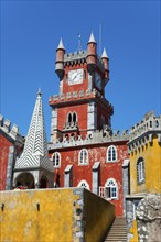 Red tower with clock and yellow façade, pointed roof and blue sky, Palácio Nacional da Pena, Pena