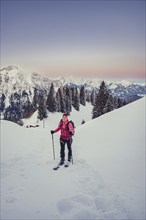 A woman's ski tour at sunrise on the Tegelberg in the Allgäu in the Ammergebirge, Bavaria, Germany,