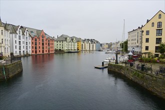 City view with coloured buildings by the sea, boats and bridge in the background, Alesund, Fylke,